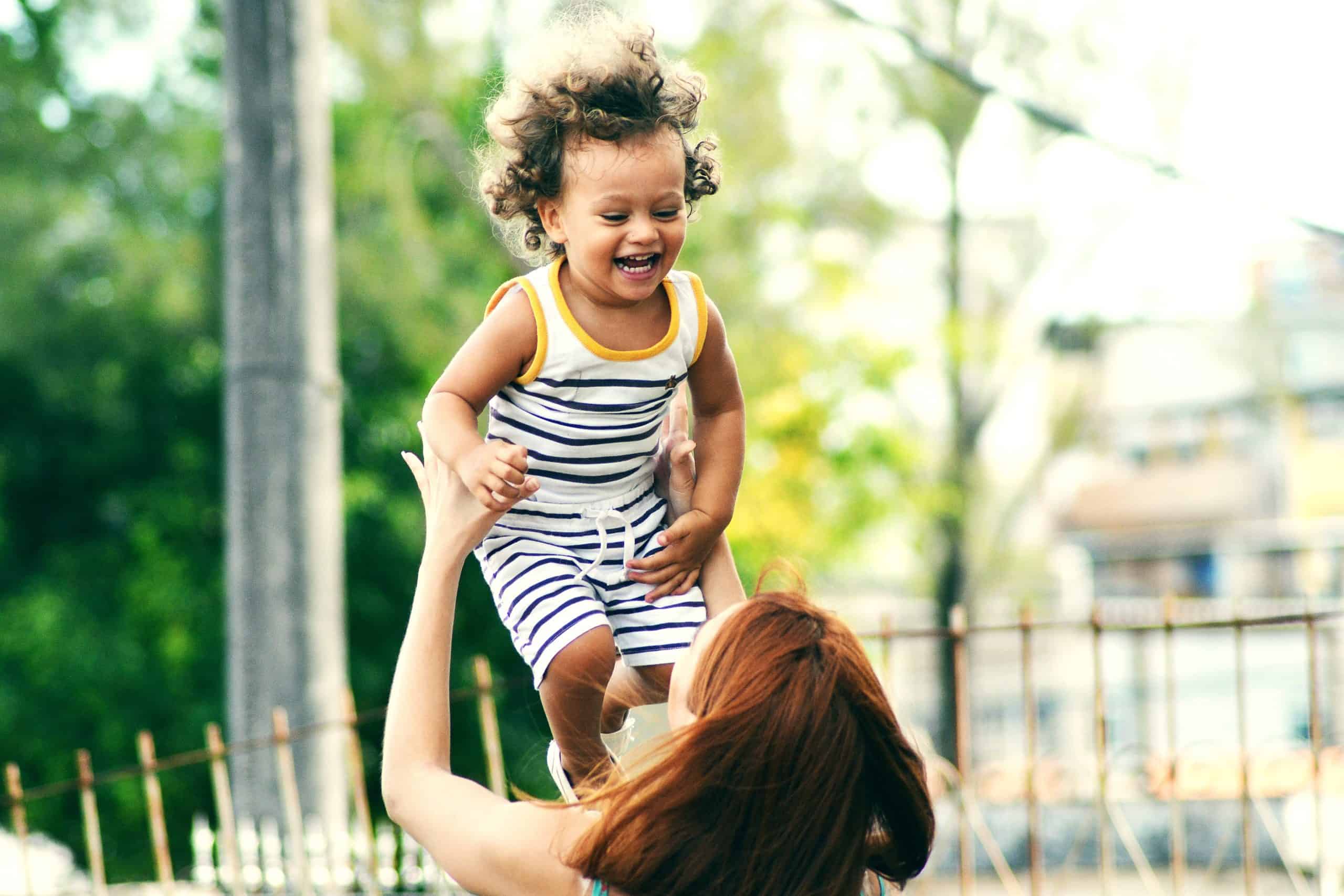 Mom holding up laughing child Give Once - Image of mother holding up a child