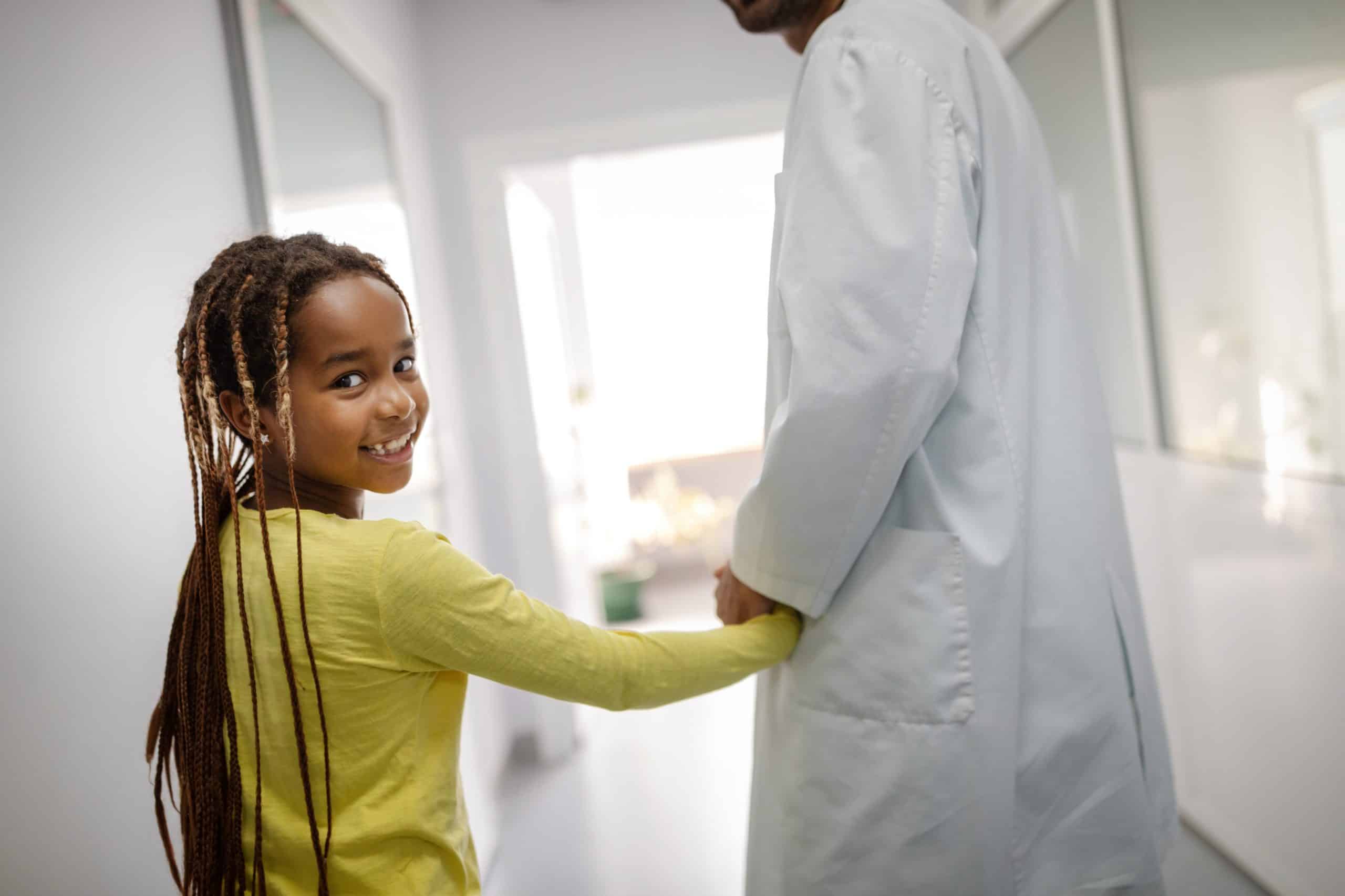 Pediatrician doctor holding young girl kid hand in hospital